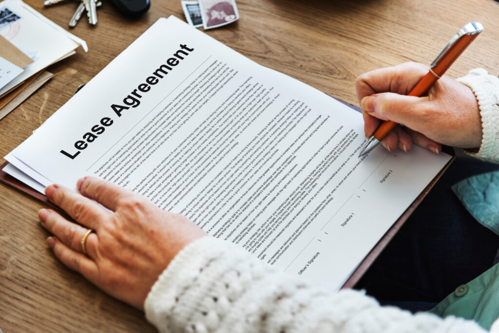 Person signing a lease agreement document on a wooden table, emphasizing tenant rights and lease termination options in Texas.