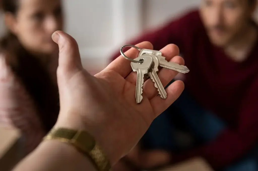 Hand holding keys, symbolizing tenant rights and lease agreements, with two individuals in the background engaged in discussion, reflecting legal services for tenants in Austin Hills.