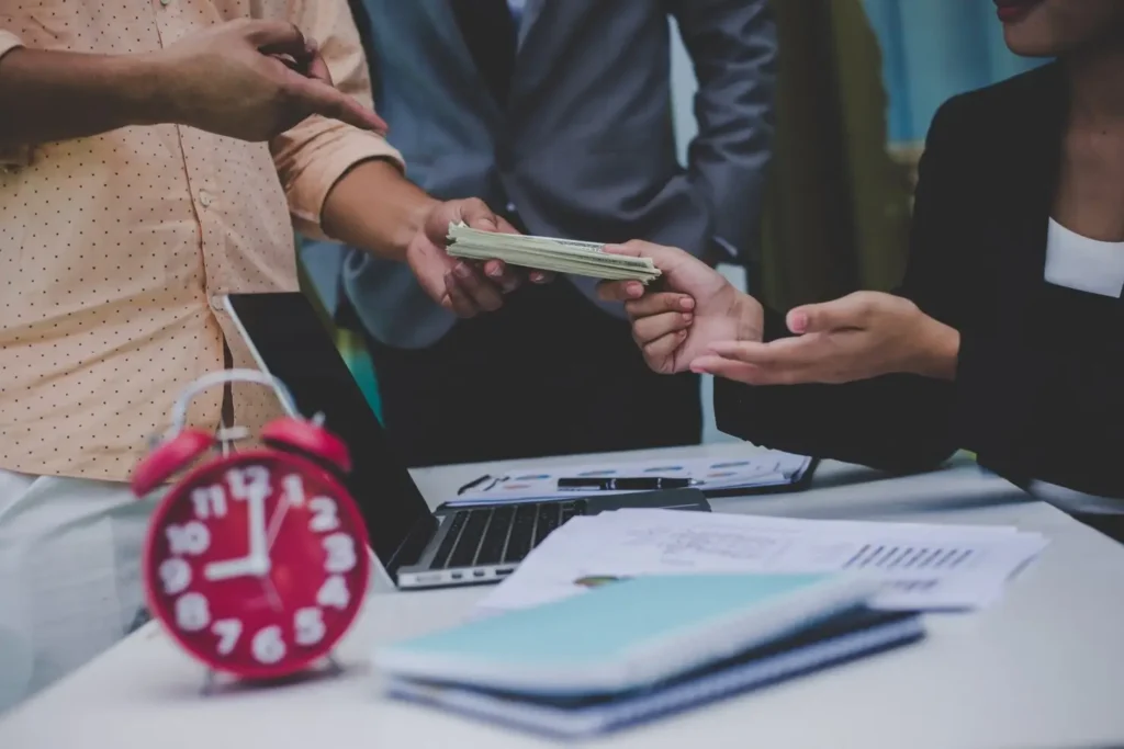 Hands exchanging cash in a legal consultation setting, with documents and a clock on the table, representing tenant rights and financial disputes in Balcones Woods.