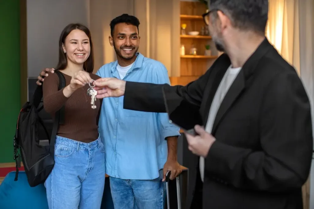 Young couple receiving keys from a landlord in a welcoming rental space, symbolizing tenant rights and new beginnings in Barton Hills.