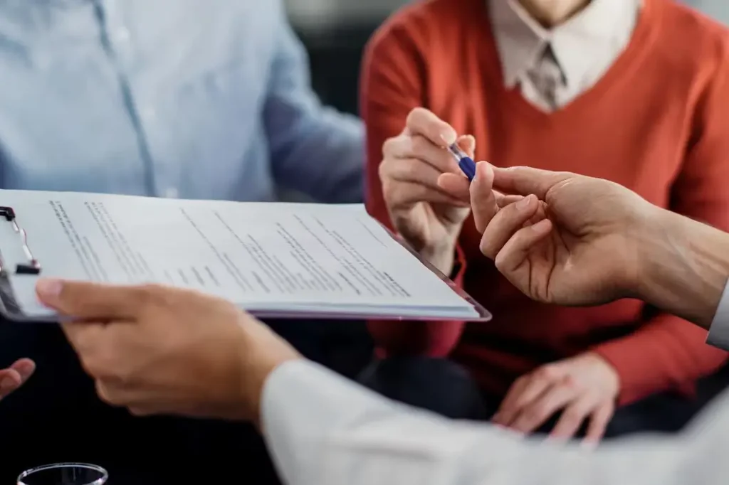 Hands exchanging a lease agreement document with a pen, symbolizing landlord-tenant legal consultation in DeSoto, Texas.