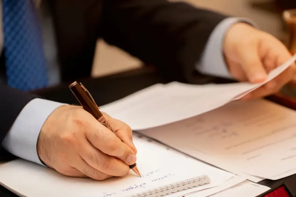 Hand of a professional man writing notes and reviewing documents related to landlord-tenant legal matters, emphasizing lease agreements and compliance with Texas law.