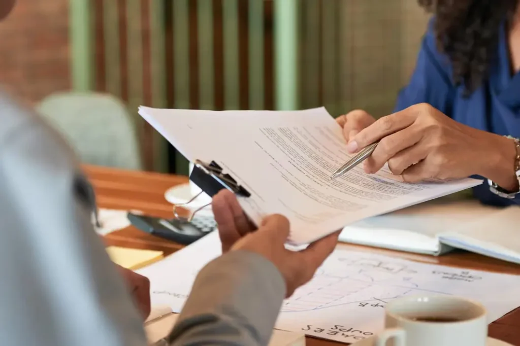 Two individuals discussing legal documents related to tenant rights and lease agreements, with a focus on a pen and paperwork, in a professional setting.