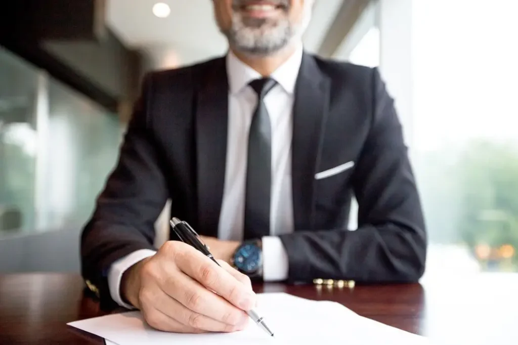 Man in a suit signing a document at a desk, representing legal services for landlords and tenants in McKinney, Texas.