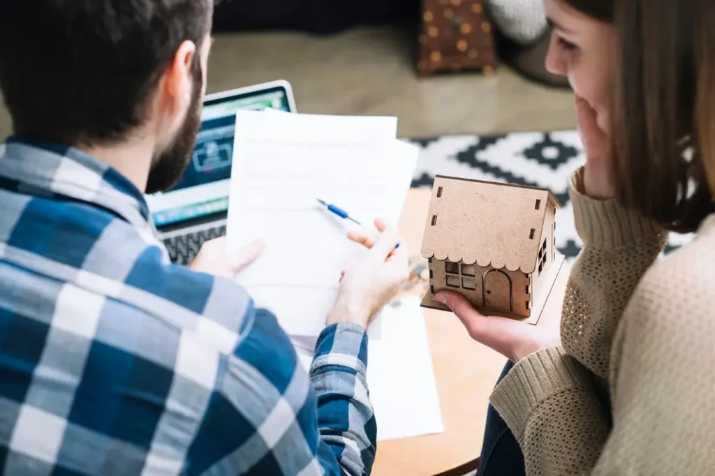 Couple reviewing lease documents with a model house, discussing tenant rights and legal services in North University.