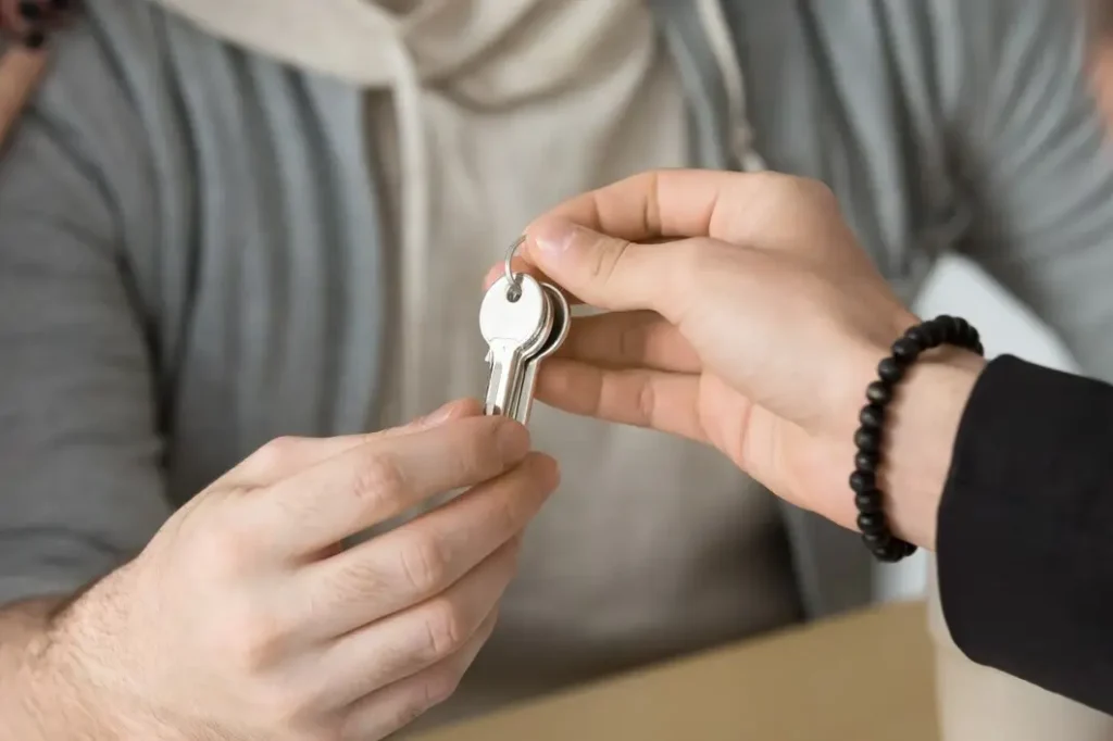 Hands exchanging keys symbolizing tenant rights and lease agreements in Scofield Farms.