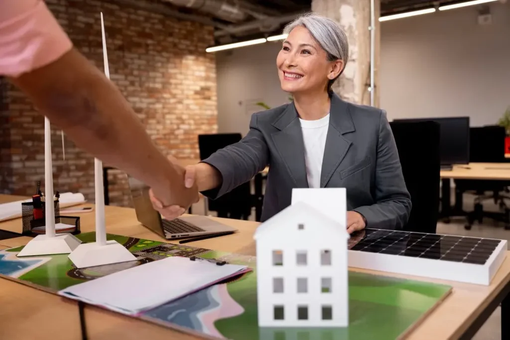 Professional woman shaking hands with a client in an office, with a model house and solar panels on the table, symbolizing tenant rights and legal advocacy in Spicewood Springs.