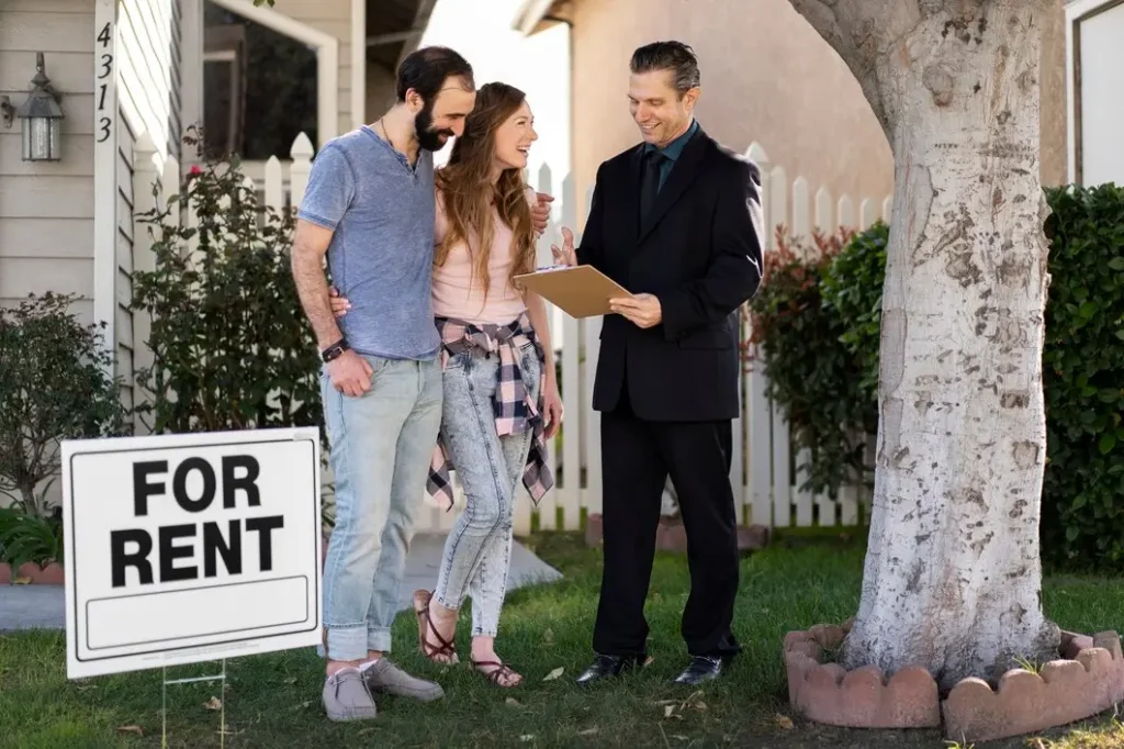 The Austin Center Couple discussing rental agreement with real estate agent in front of house with "For Rent" sign, symbolizing tenant rights and housing services in Austin.