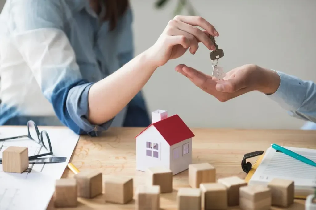 Hands exchanging keys above a small model house, symbolizing tenant rights and landlord-tenant agreements in Triangle State, Texas.