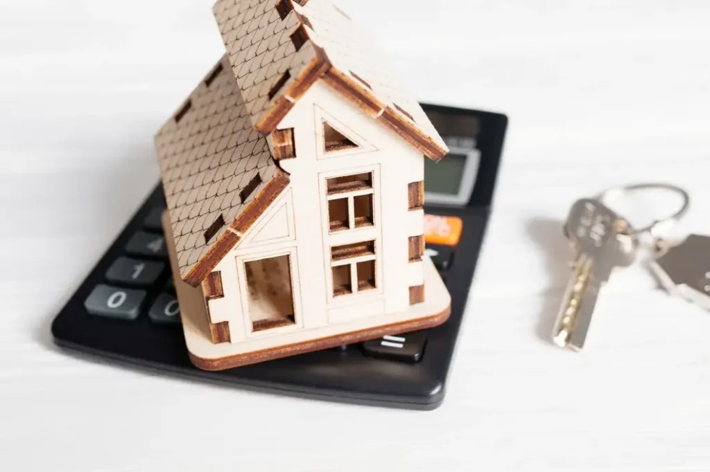 Wooden model house on a calculator with keys, symbolizing tenant rights and financial considerations in landlord-tenant disputes in Village at Walnut Creek.