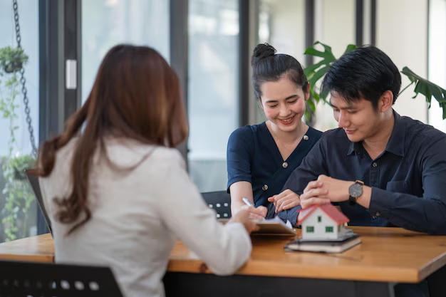 Couple consulting with a tenant rights attorney at a table, discussing lease agreements, with a small house model and documents present, emphasizing tenant legal services in Lacoste, TX.