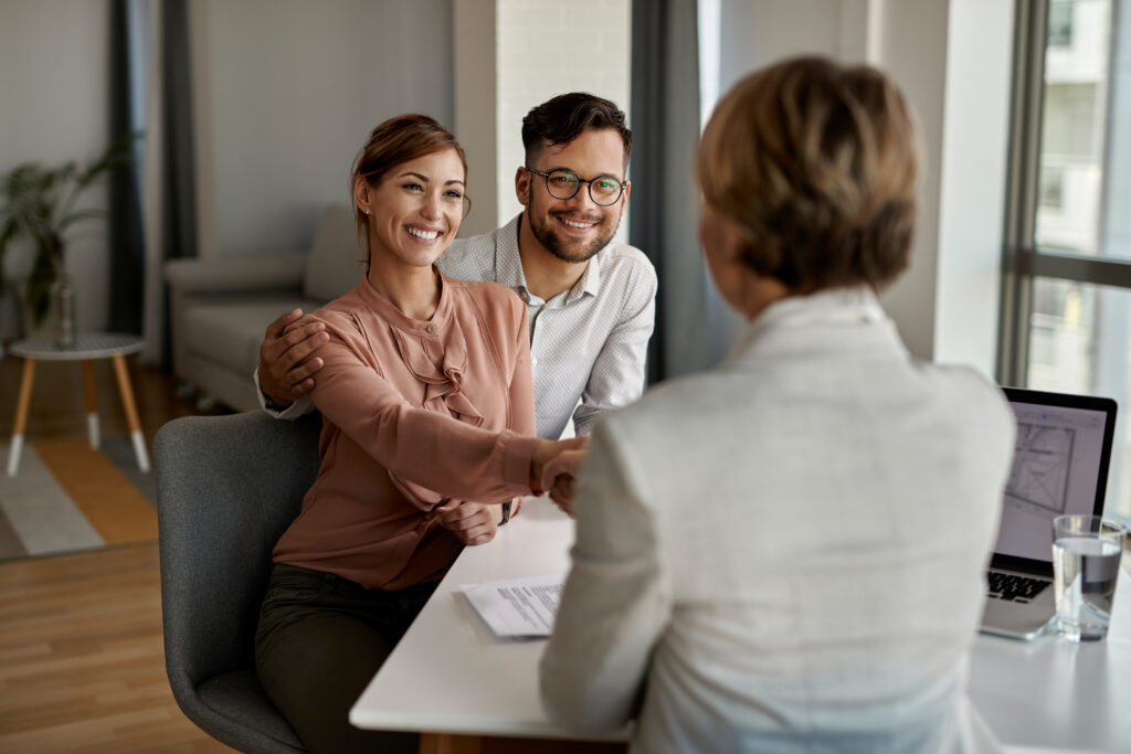 Young couple shaking hands with a tenant rights attorney in an office setting, discussing legal representation for tenant issues in Hill Country Village, Texas.